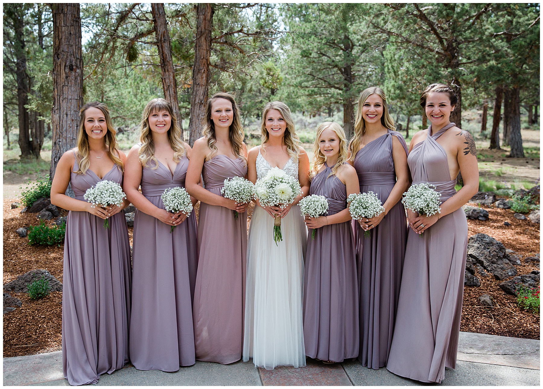 McKenna with bridesmaids on either side wearing different shades of lavender dresses in different styles.