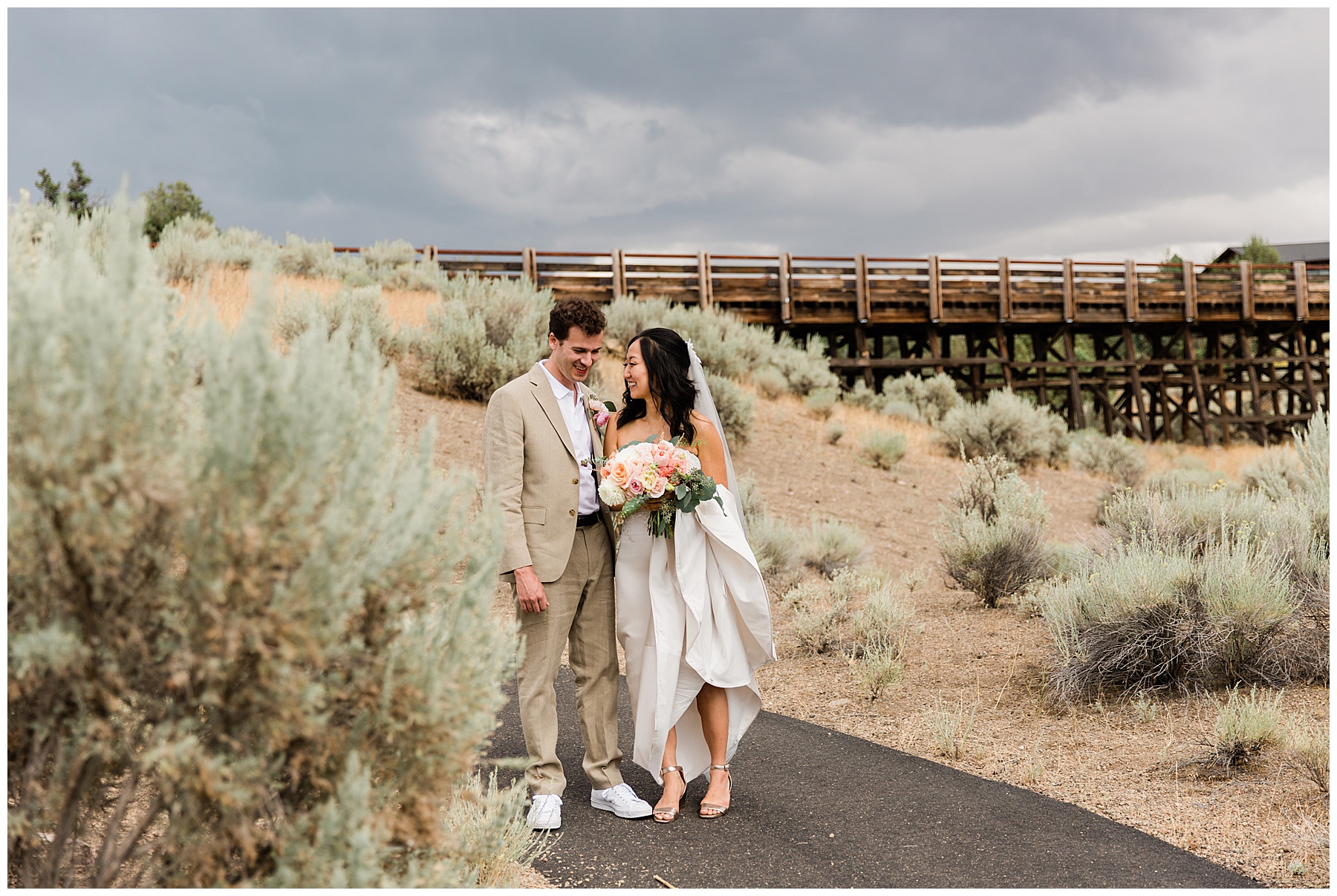 Bride and groom walk through Brasada Ranch Bend Oregon Resort while storm clouds roll in from behind. 